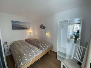 A bedroom with a bed, bedside tables, a mirror, and a window. - Finkennest - Pavilion (Cuxhaven)
