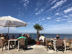 An outdoor seating area with tables and chairs, overlooking the sea. - Finkennest - Pavilion (Cuxhaven)