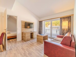A modern hotel room with a bed, a desk, a sofa, a TV, and a balcony with a view. - Gorgeous 2-bedroom apartment right on the ski slope at Feldberg (Feldberg (Schwarzwald))