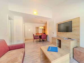 Ein modernes Wohnzimmer mit einer Couch, einem Couchtisch und einem an der Wand befestigten Flachbildfernseher.