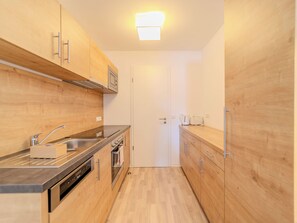 Eine moderne Küche mit Holzschränken, Edelstahlgeräten und einer weißen Tür.