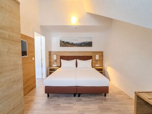 Ein modernes Hotelzimmer mit einem großen Bett, einem Holzkopfteil, Nachttischen und einem Gemälde an der Wand.
