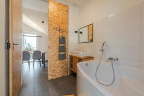 A modern bathroom with a bathtub, a sink, and a mirror. - Holiday Home Lukc (Kobarid)