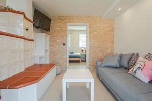A modern living room with a sofa, a white coffee table, and a television mounted on the wall. - Holiday Home Lukc (Kobarid)