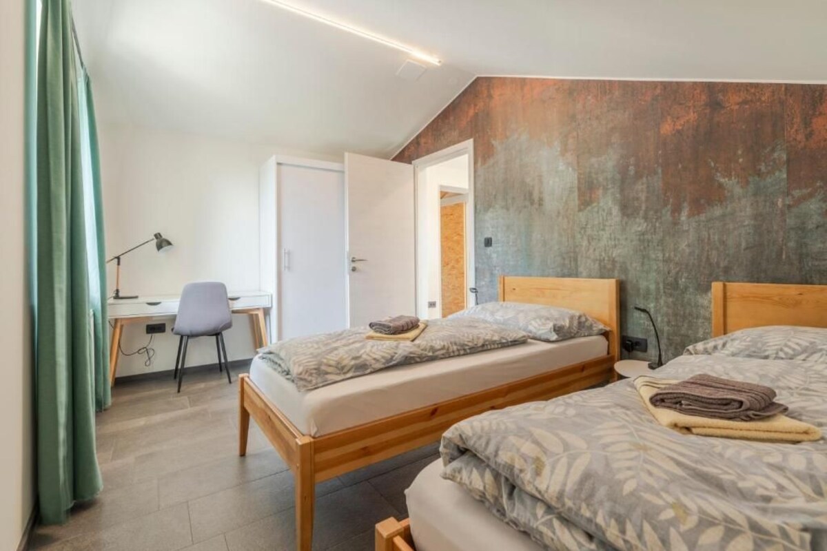 A bedroom with two beds, a desk, and a chair.