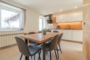 A modern kitchen with white cabinets, a wooden countertop, and a black range hood. - Holiday Home Lukc (Kobarid)