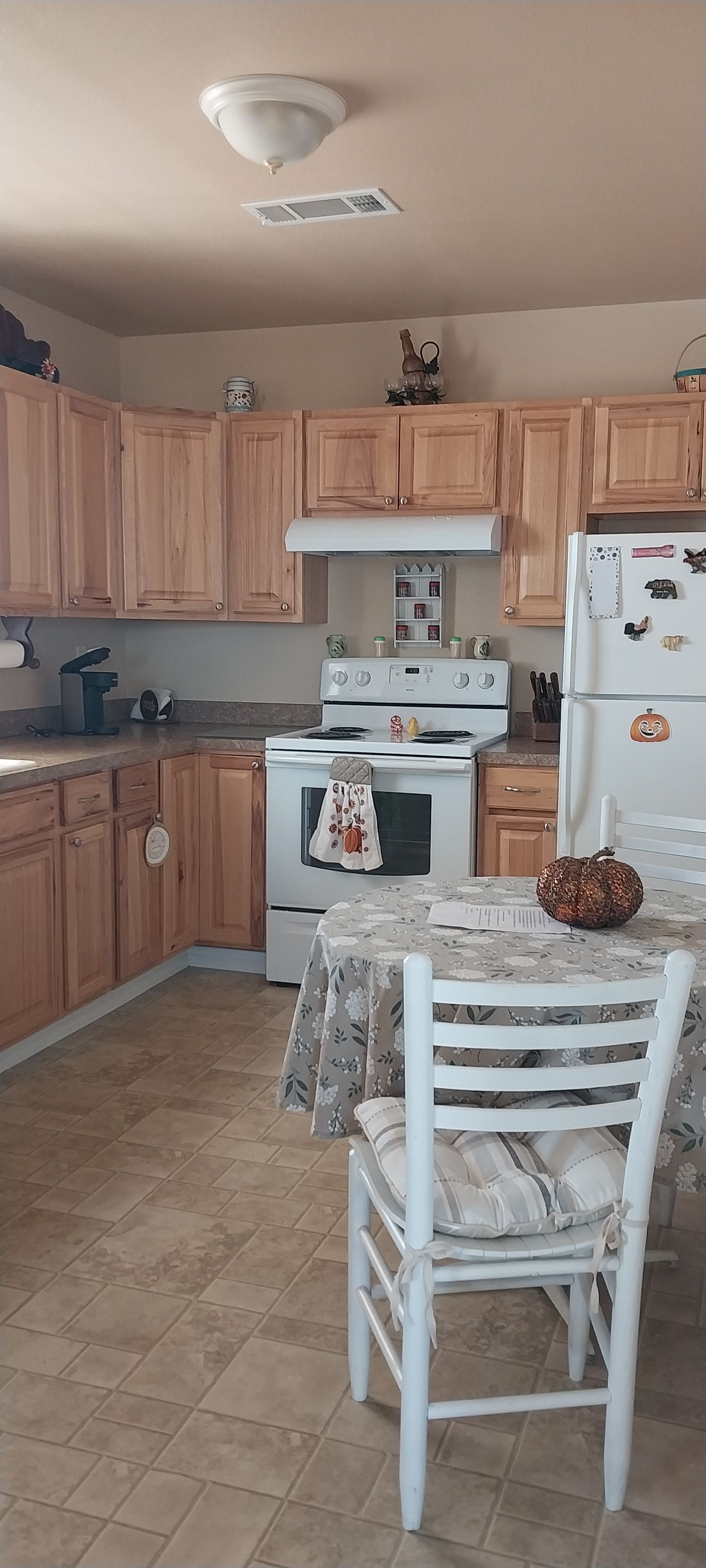 Une cuisine avec des meubles de rangement en bois, une cuisinière, un réfrigérateur et une table à manger avec des chaises.