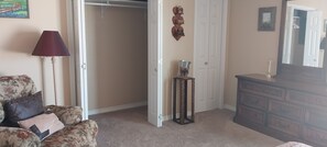 A room with a floral sofa, a wooden dresser, a mirror, and a door leading to another room.