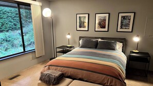 Une chambre à coucher avec un grand lit, des lampes de chevet, un banc et des œuvres d’art encadr ées accrochées au mur.