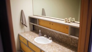 Une salle de bain avec un lavabo blanc, un miroir et une serviette accrochée au mur.