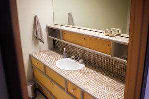 Un baño con un lavamanos blanco, un espejo y una toalla colgada en la pared.
