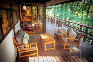 Una terraza de madera con mobiliario exterior, incluyendo un sofá, sillas y una mesita.