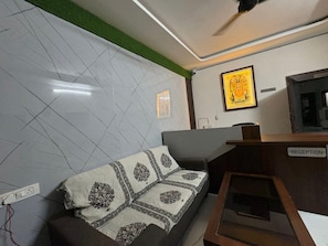 Zona de recepción con mostrador, sofá con manta estampada y pared con diseño geométrico.