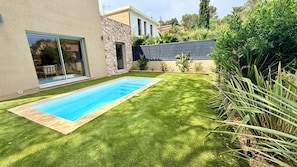 A swimming pool with a stone wall and a grassy lawn. - New villa for 6 people - Pool - Beach 800 m away (Fréjus)