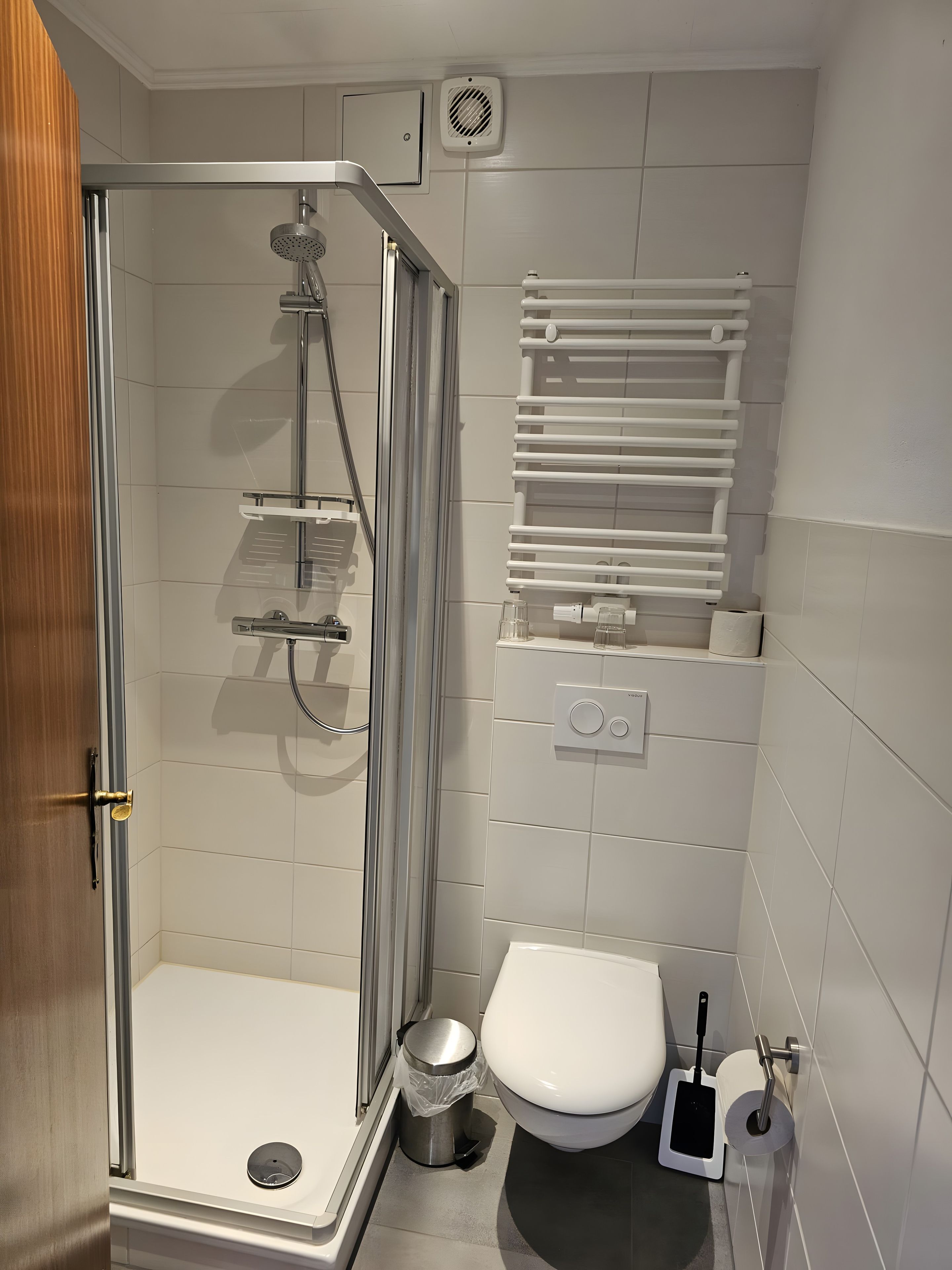 Ein modernes Badezimmer mit einer Duschkabine, einer Toilette und einem Mülleimer.