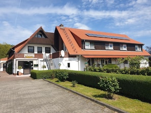 Um edifício de dois andares com uma placa indicando 'Pension Dalina' e um painel solar no telhado.