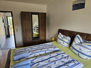 Quarto com cama, guarda-roupa e espelho.