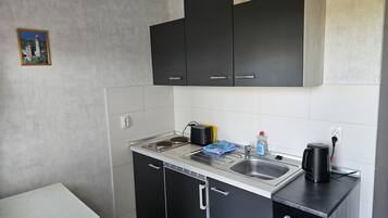 Eine kompakte Küche mit schwarzen Schränken, einer Edelstahl-Spüle und einer Kaffeemaschine.
