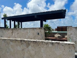 Eine steine Mauer mit einer Pergola darüber.