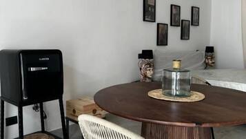 Une table de salle à manger ronde, surmontée d’un set de table en fibres tressées, avec un haut-parleur noir et une chaise en osier.