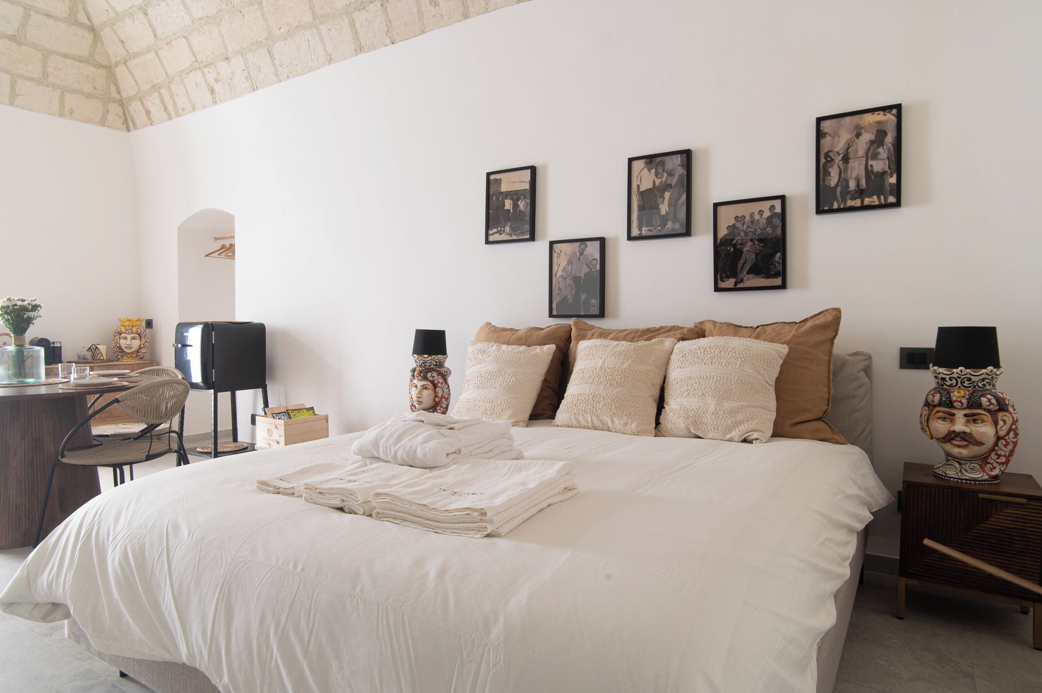 Una camera da letto ordinata con un letto, cuscini e un comodino.
