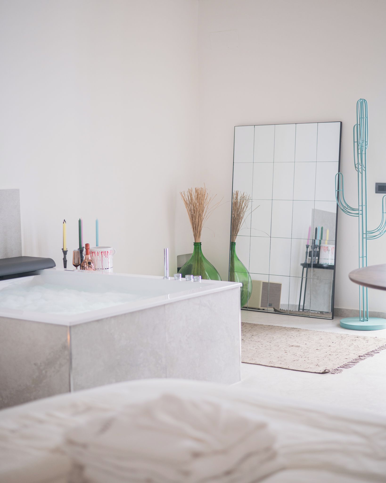 Une salle de bain moderne avec une baignoire, un miroir et une décoration à base de cactus.