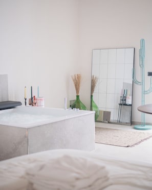 Um banheiro moderno com banheira, espelho e um cacto decorativo.