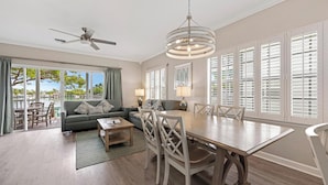 A spacious living room with a dining area, large windows with shutters, a ceiling fan, and a view of the outdoors. - Villa 7079 on Duck Key - Boat Slip Available (Marathon)