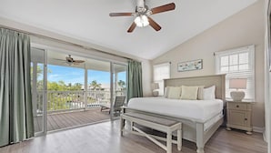 A bedroom with a large bed, a bench, a ceiling fan, and a view of a pool and palm trees through a sliding door. - Villa 7079 on Duck Key - Boat Slip Available (Marathon)