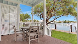 A covered outdoor seating area with a view of a body of water and a tree. - Villa 7079 on Duck Key - Boat Slip Available (Marathon)