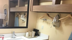 A bathroom with a white sink, a mirror, a towel rack, and a hanging shower curtain. - Days Inn Batesville! Your room for the Top 10 SEC Clash. 2 Double Beds. (Batesville)