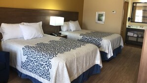 A hotel room with two beds, a nightstand, a lamp, a mirror, and a bathroom area. - Days Inn Batesville! Your room for the Top 10 SEC Clash. 2 Double Beds. (Batesville)