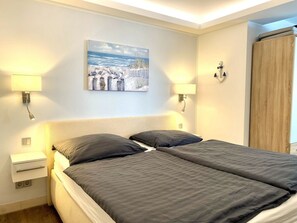 A bedroom with a double bed, two bedside tables, a nightstand, and wall-mounted lamps. - "beach Hideaway" in Binz (Binz)