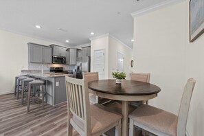 A modern kitchen with grey cabinets, stainless steel appliances, and a central island with bar stools. - Luxury Lost Bay Retreat in Orange Beach, AL, 3BR Townhome Near Beach (Orange Beach)