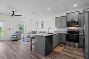 A modern kitchen with grey cabinets, stainless steel appliances, and a central island. - Luxury Lost Bay Retreat in Orange Beach, AL, 3BR Townhome Near Beach (Orange Beach)