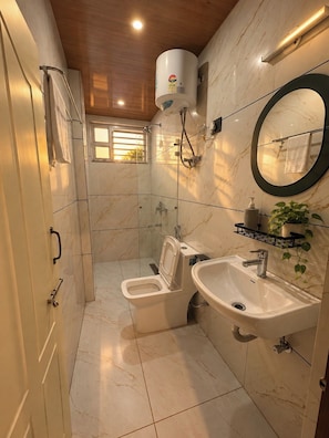 Et badeværelse med toilet, bidet, vask og spejl.