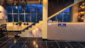 A reception area with a marble reception desk, a staircase, and potted plants. - DORJE HILL STAY DARJEELING - KANCHENJUNGA VIEW COZY HOMESTAY (Darjeeling)