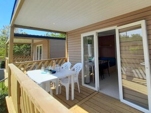 A covered outdoor area with a table and chairs, a sliding glass door, and a wooden deck. - Bright & Airy Riviera Getaway (Hyères)