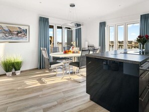 A modern kitchen with a central island, dining area with chairs, and a view of the city. - Holiday Apartment With 4 Bedrooms (Kappeln)