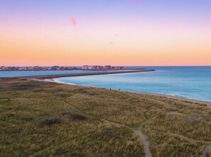 A coastal landscape with a beach, grassy dunes, and a distant shoreline with buildings. - Apartment in Olpenitz With Swimming Pool (Kappeln)