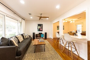 A modern living room with a sofa, coffee table, and a dining area with bar stools. - Charming 4-bedroom split-level home in North Charleston (North Charleston)