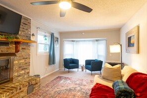 A living room with a fireplace, two sofas, a rug, and a television. - Charming 4-bedroom split-level home in North Charleston (North Charleston)