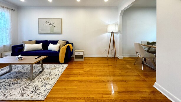 Uma sala de estar moderna com um sofá azul, uma mesa de centro, um abajur e um espaço de jantar com mesa e cadeiras.