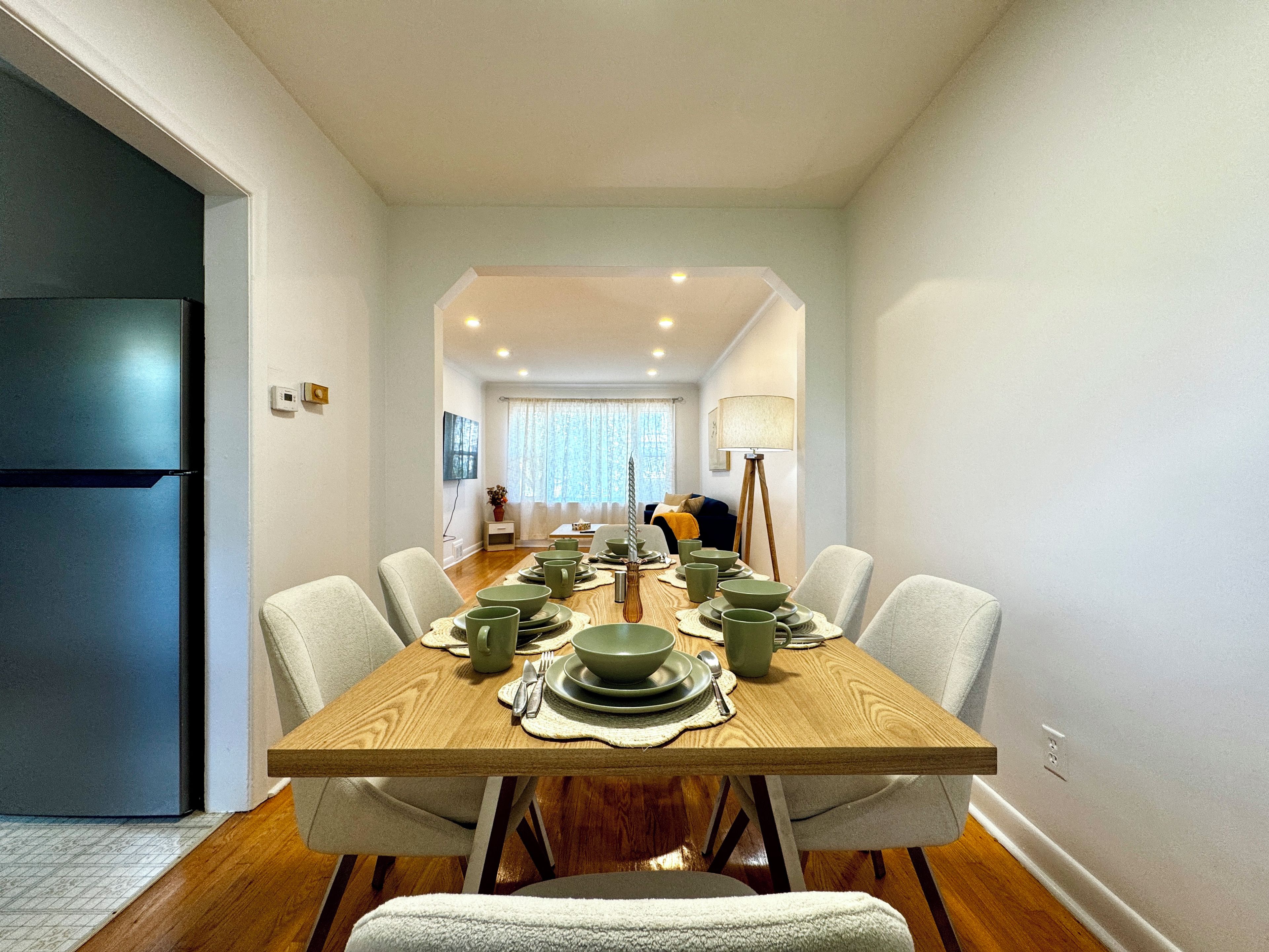 A dining area with a wooden table set for four, surrounded by chairs.