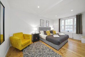 A bedroom with a bed, bedside tables, a chair, a window, and a view. - Eton High Street 5-Bed Townhouse | Castle Views | Parking (Eton)
