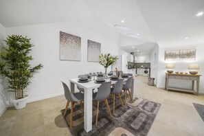 A modern dining area with a white table set for six, grey chairs, and a potted plant. - Eton High Street 5-Bed Townhouse | Castle Views | Parking (Eton)