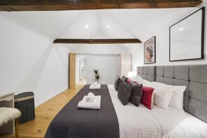 Une chambre avec un grand lit, un plafond en bois et un tableau encadré au mur.