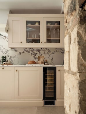 A kitchen with marble backsplash, wooden cabinets, and a built-in wine cooler. - Beautifully renovated cottage in Burford (Oxfordshire)
