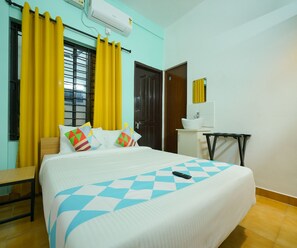 A hotel room with a bed, a desk, a chair, and a window with curtains. - Deluxe Room Green Heaven (Kanayannur)