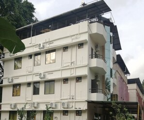 A multi-story building with balconies, air conditioning units, and a flat roof. - Deluxe Room Green Heaven (Kanayannur)